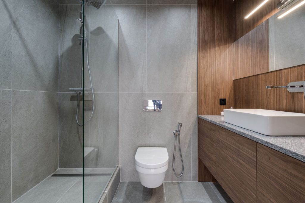 חדר רחצה עם מקלחון walk-in, קרמיקה אפורה וארון רחצה מעץ